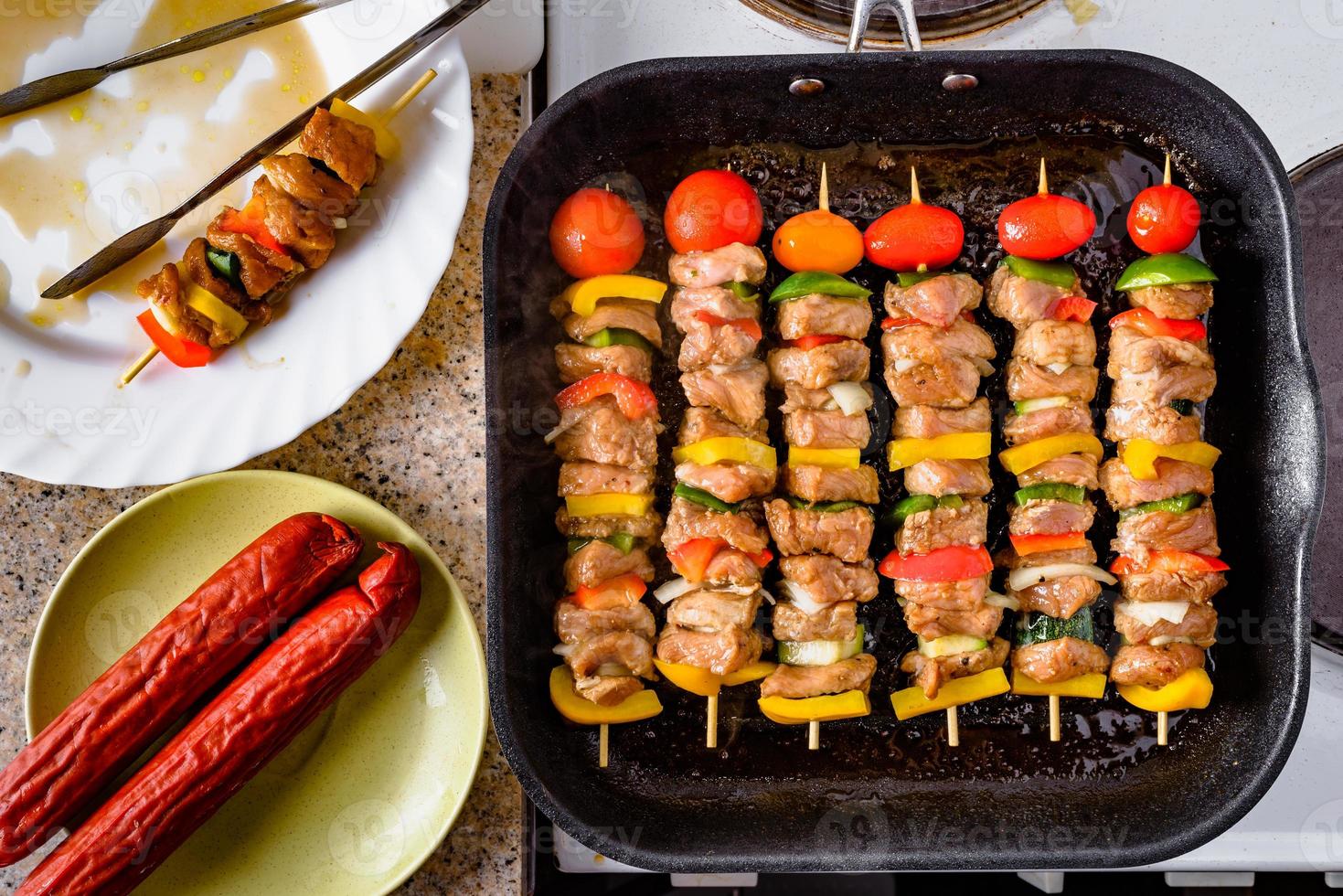 Grilled skewers on wooden sticks, pork meat and vegetables on grill. photo