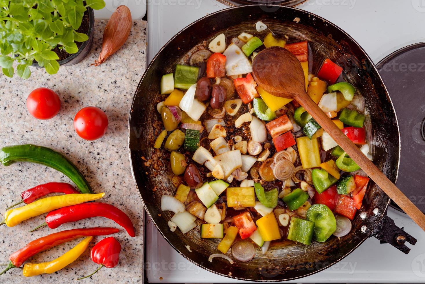 Mix of fresh vegetables fried in the rustic pan, fresh hot chili peppers, tomato and herbs. photo