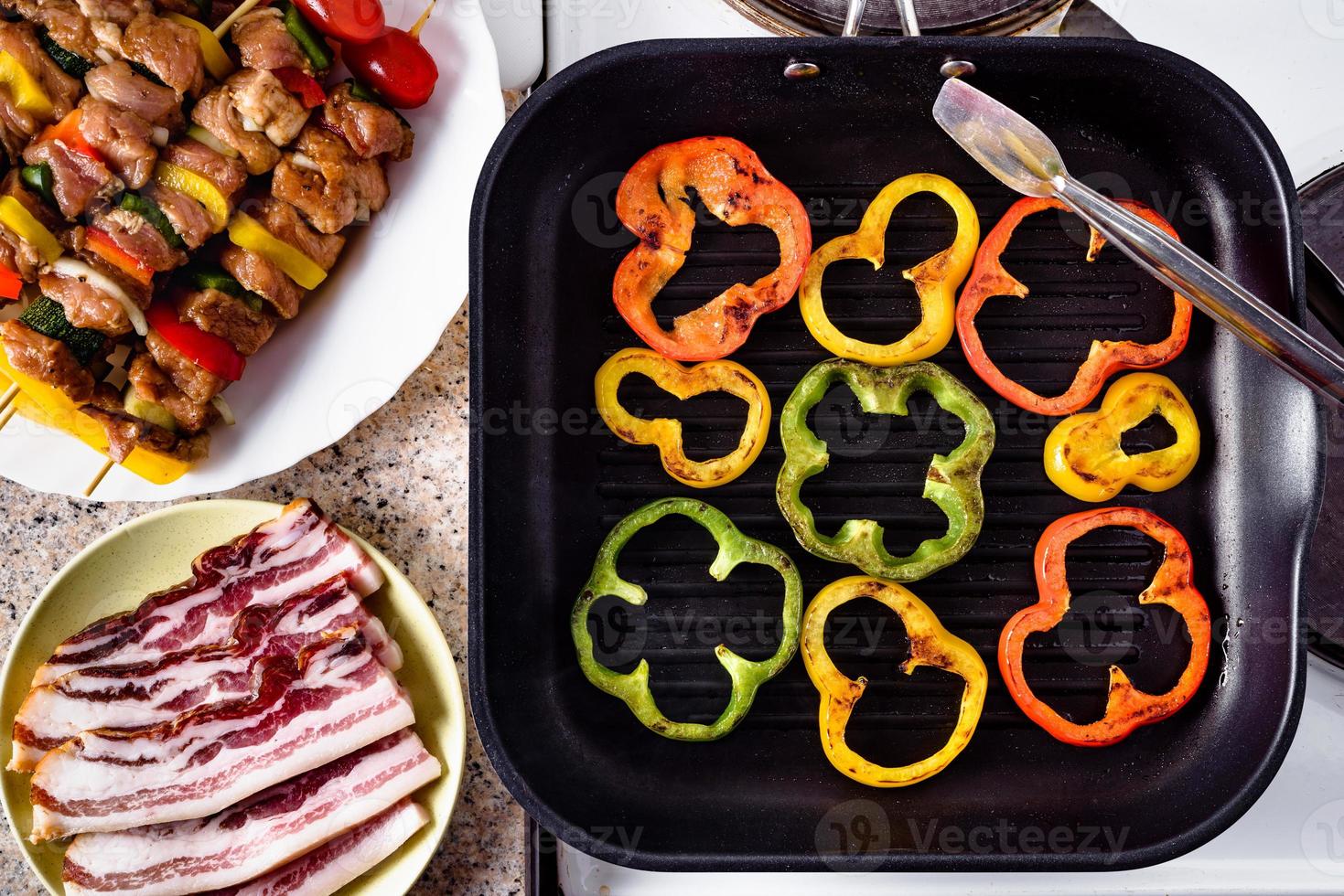 Grilled pepper. Bacon and raw pork skewers ready for grilling. photo