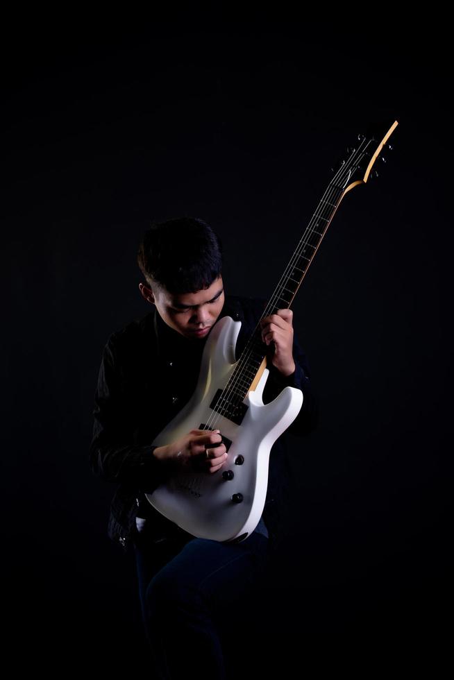 Joven en chaqueta de cuero negro con guitarra eléctrica en studio foto