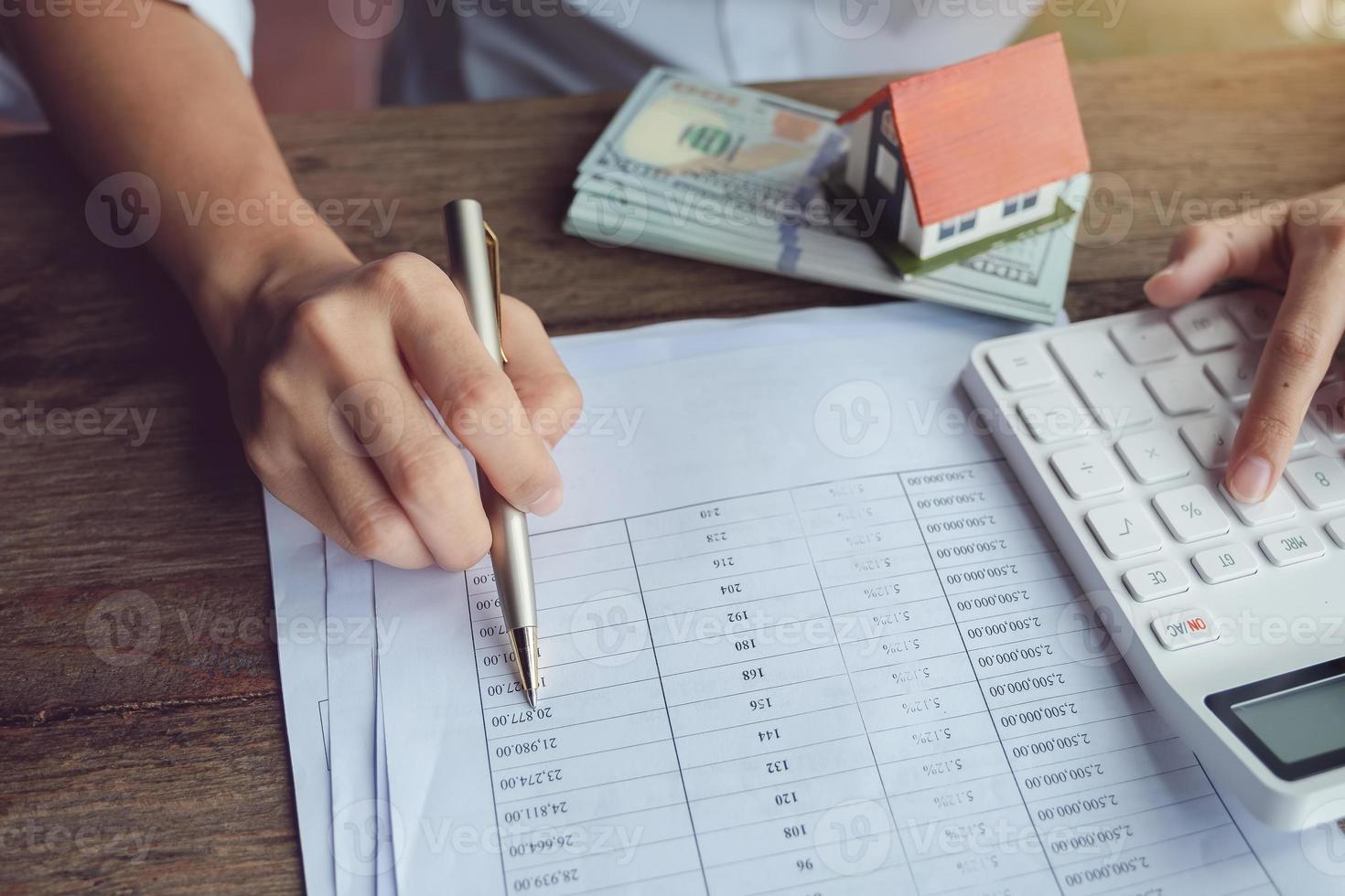 los clientes utilizan bolígrafos y calculadoras para calcular los préstamos para la compra de una vivienda de acuerdo con los documentos de préstamo recibidos del banco foto