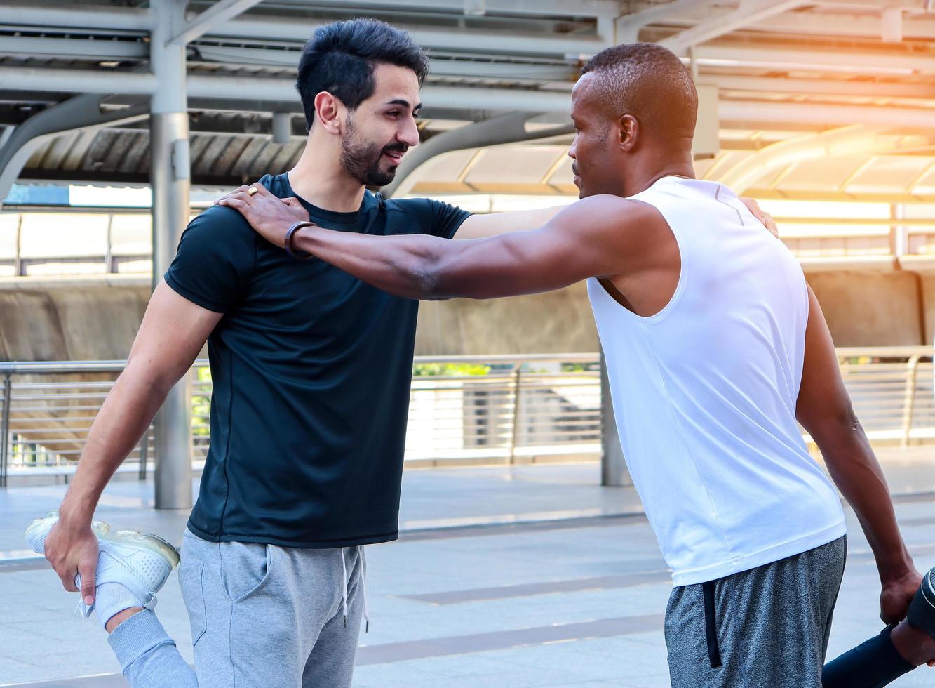 Two handsome men wearing sportswear are warming up their bodies before exercising outdoors in the city photo