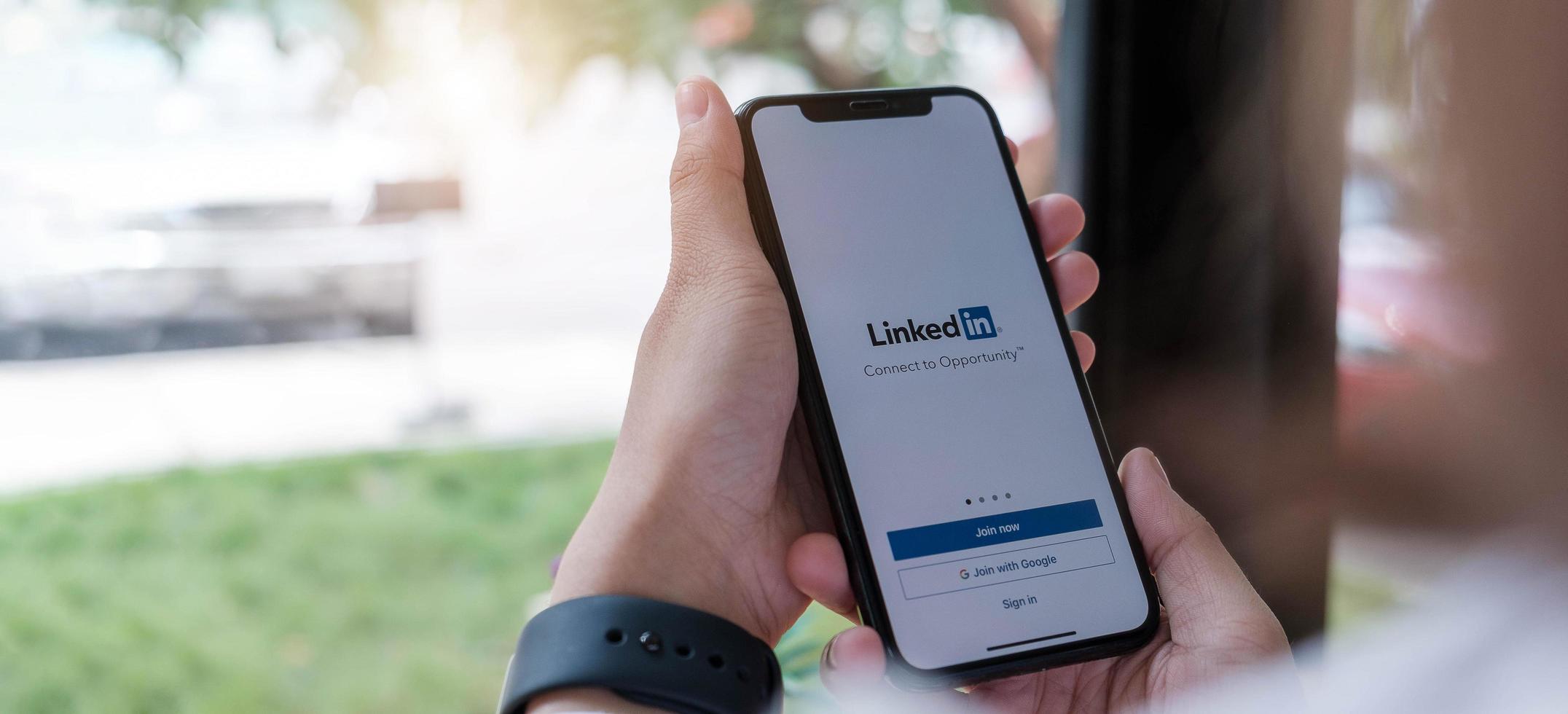 chiang mai, tailandia, 12 de diciembre de 2020: una mujer sostiene el iphone x de apple con la aplicación de linkedin en la pantalla. linkedin es una aplicación para compartir fotos para teléfonos inteligentes.