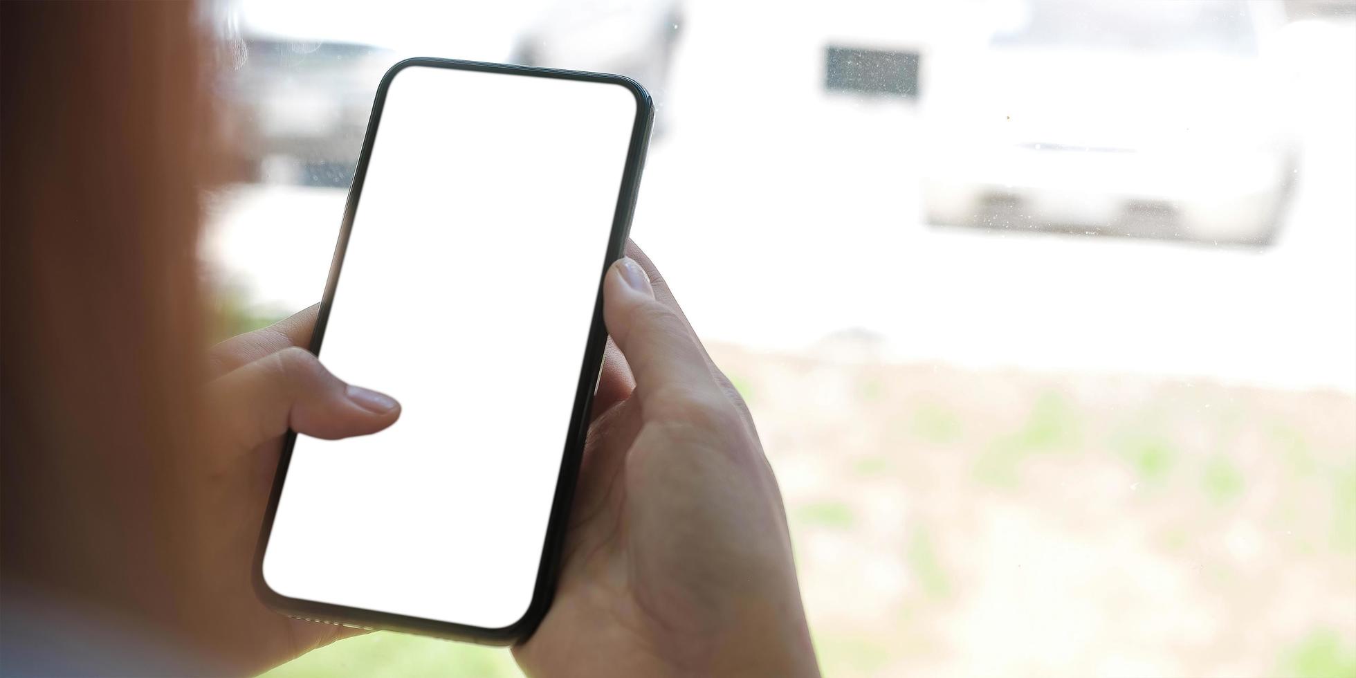 Close up of person holding a cell phone with a white blank screen photo