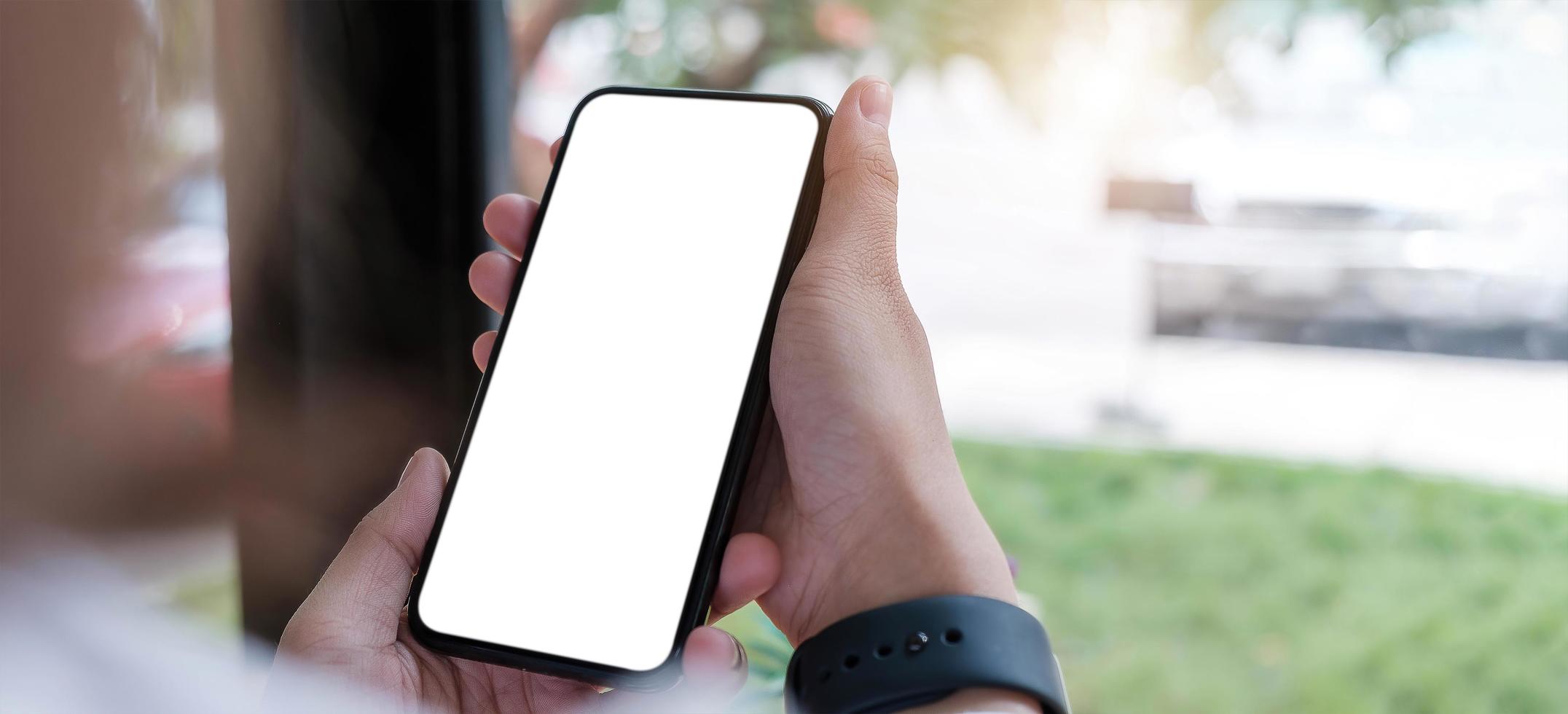 Close up of person holding a cell phone with a white blank screen photo
