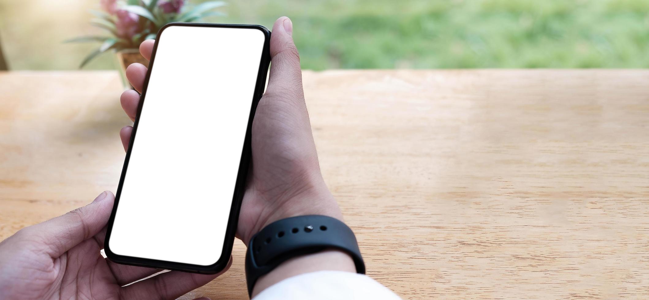 Close up of person holding a cell phone with a white blank screen photo