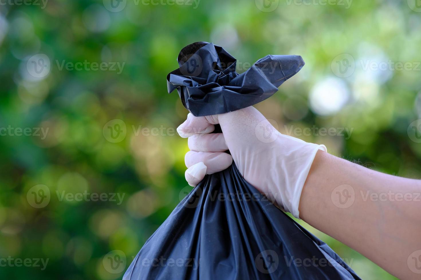 Hand holding garbage bag on green bokeh background and save the world and recycle concept photo