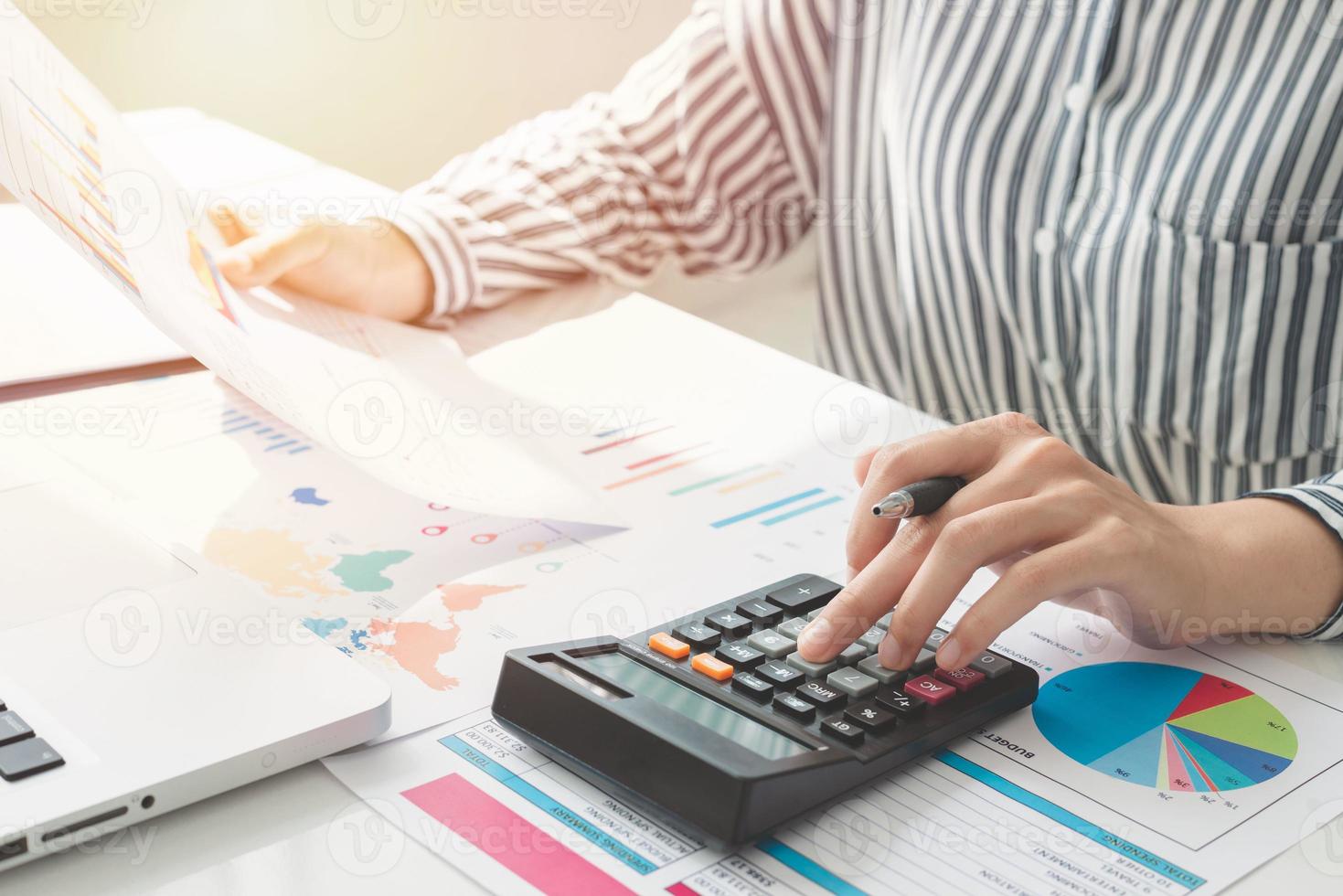 Businesswoman using a calculator and writing notes. Taxes, savings, finances, and economy concept photo