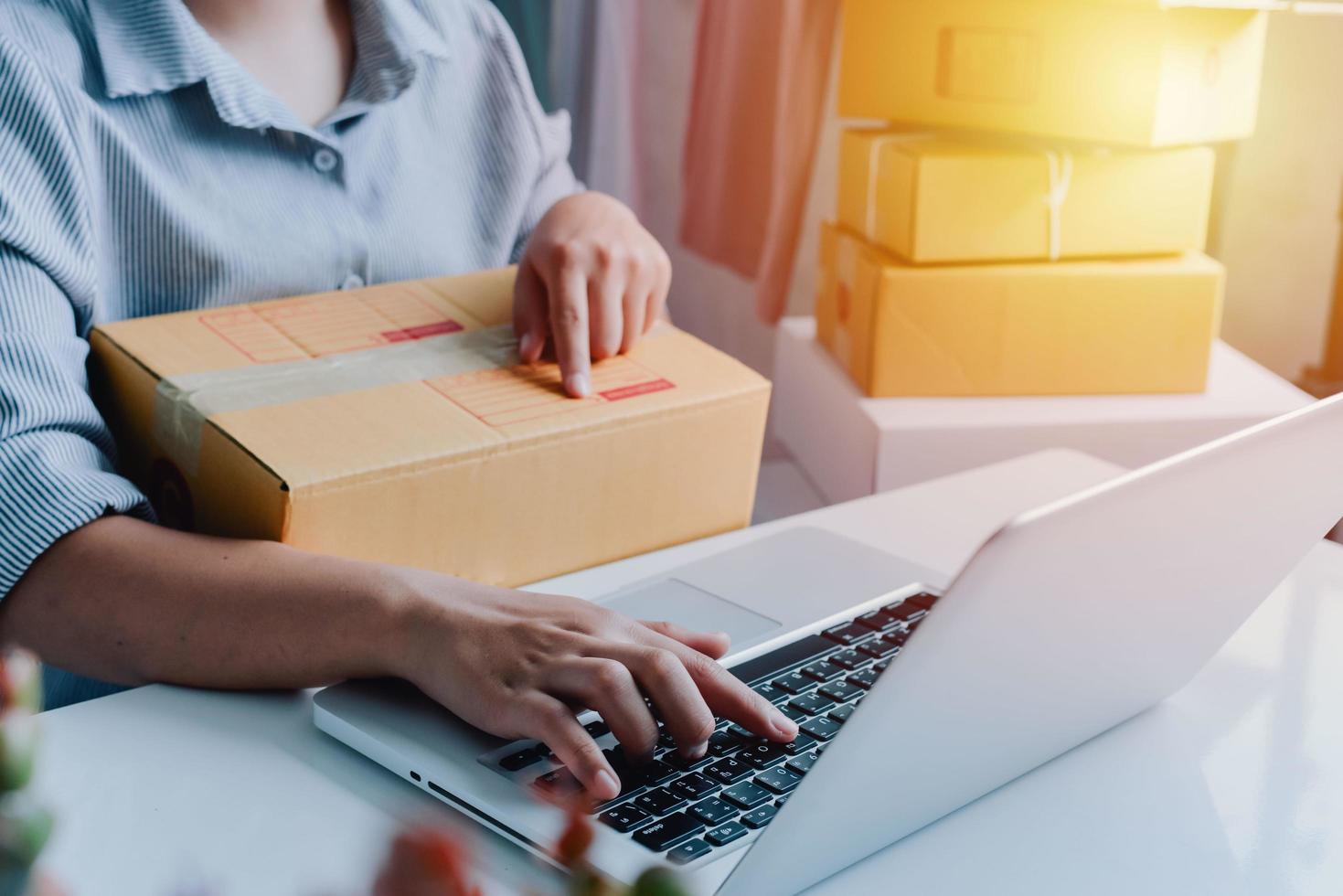 Vista de cerca de la tienda en línea de la mujer, vendedor propietario de una pequeña empresa, paquete de embalaje del empresario, caja de envío postal que prepara el paquete de entrega sobre la mesa, concepto de negocio autónomo empresarial foto