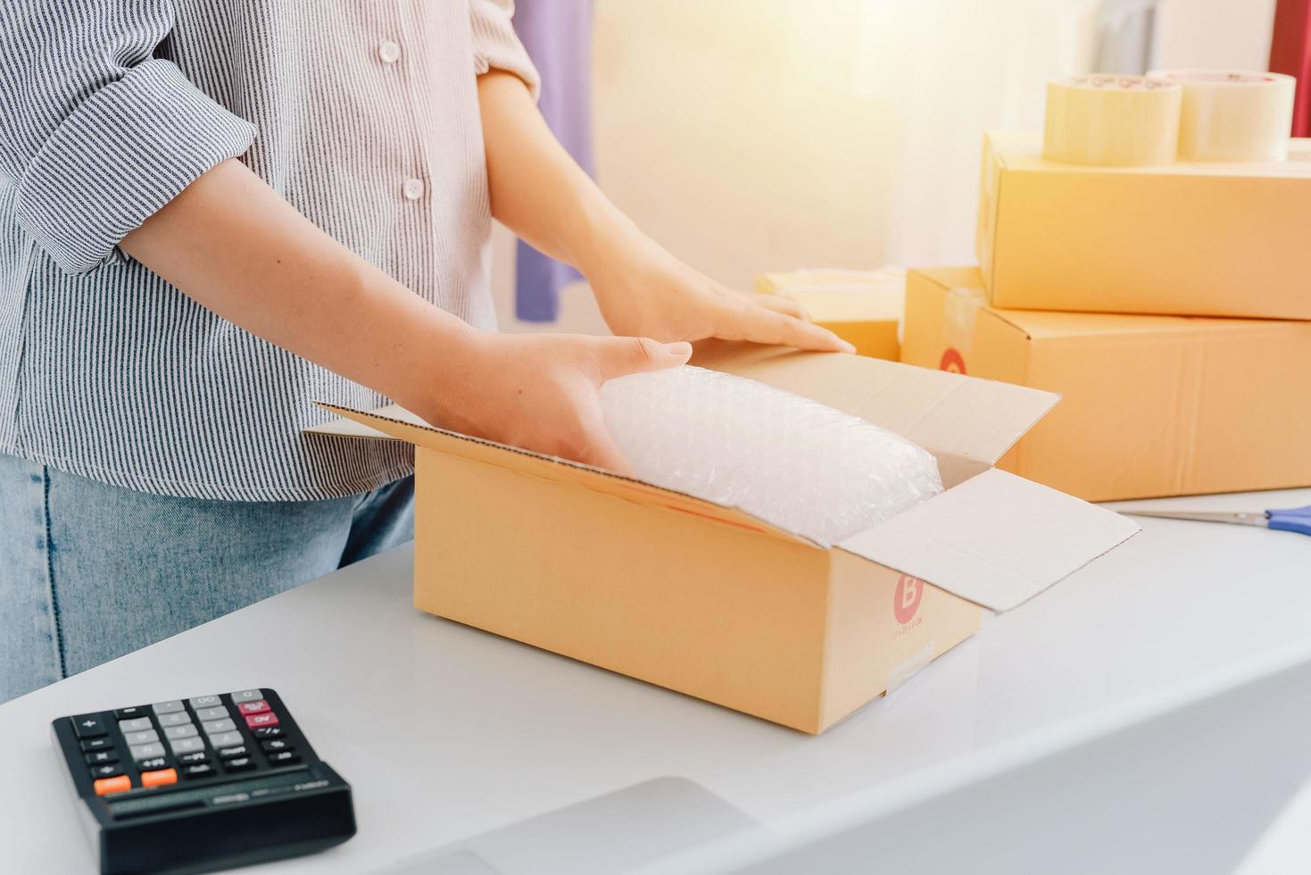 Vista de cerca de la tienda en línea de la mujer, vendedor propietario de una pequeña empresa, paquete de embalaje del empresario, caja de envío postal que prepara el paquete de entrega sobre la mesa, concepto de negocio autónomo empresarial foto