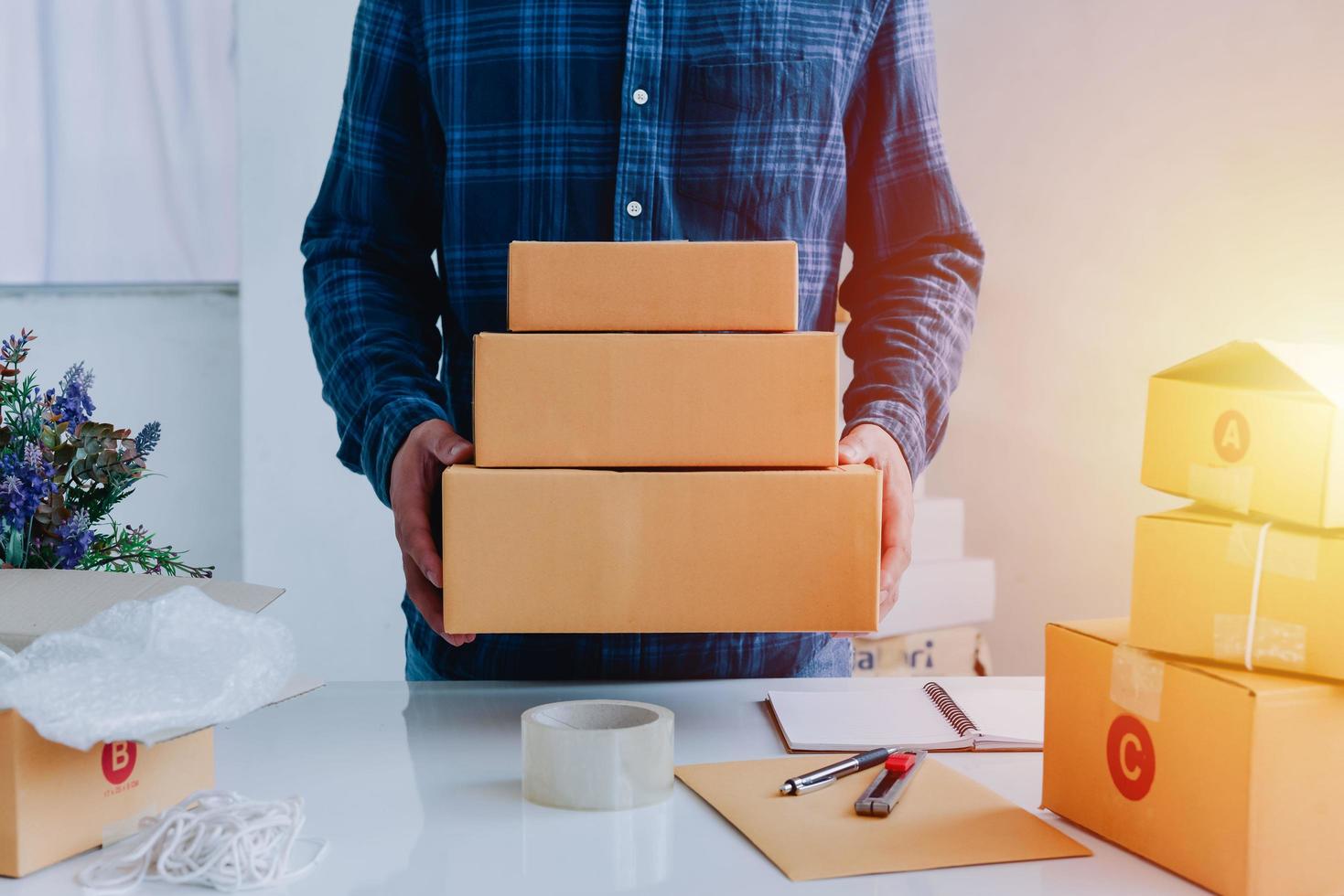 Close-up view of man's online store, small business owner seller, entrepreneur packing package post shipping box preparing delivery parcel on the table, entrepreneurial self-employed business concept photo