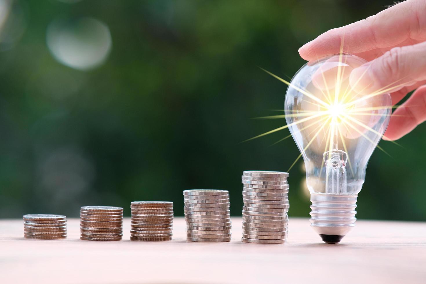 Businessman hand holding light bulb with money coins photo