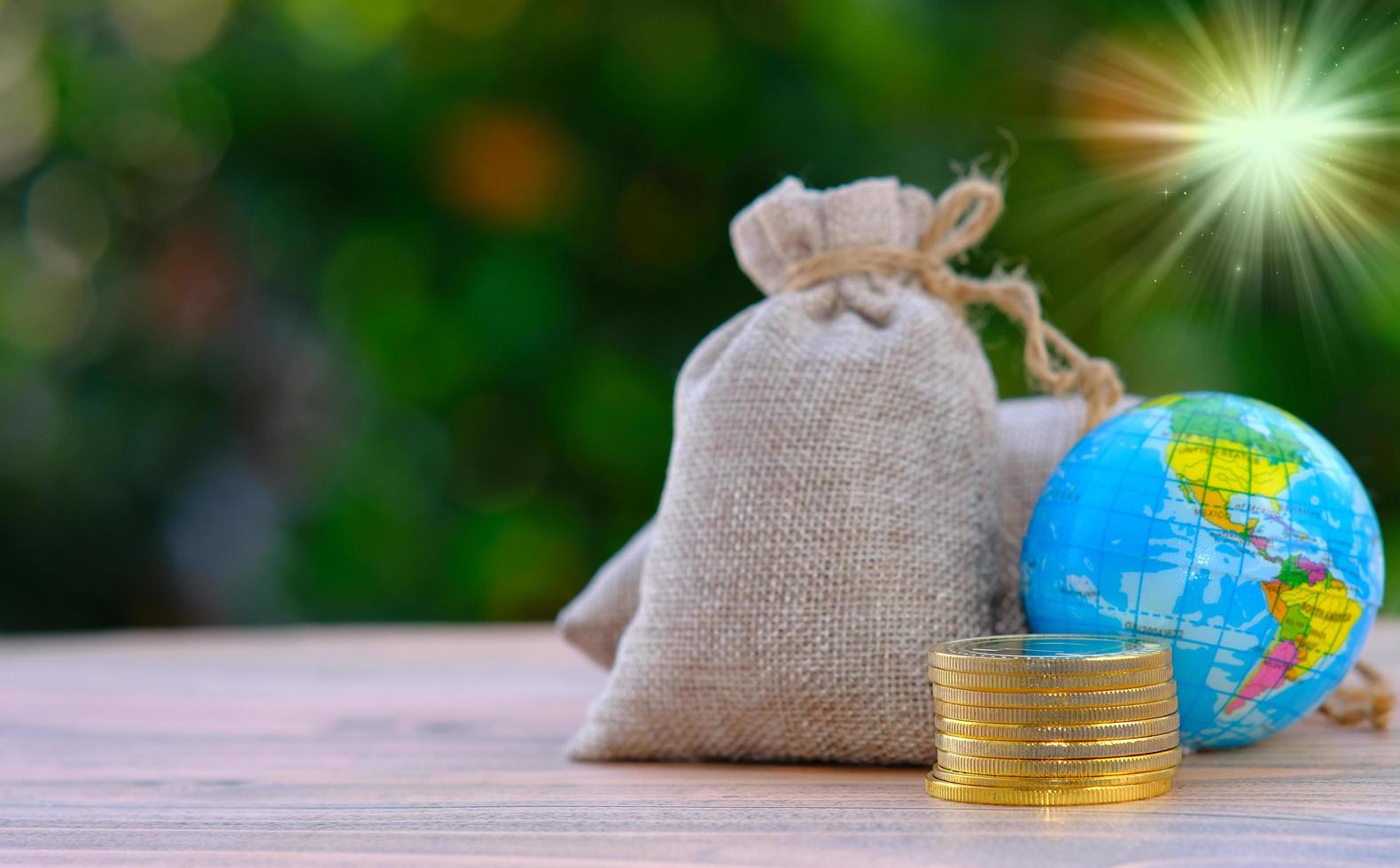 Earth and coins on wooden table and saving money and business growth concept photo