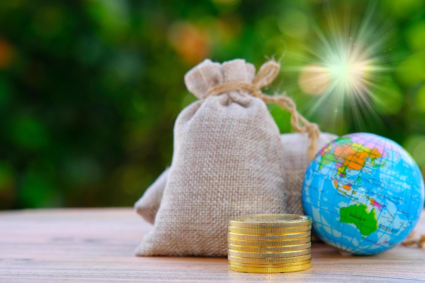 Bolsa de dinero con monedas y un globo terráqueo sobre un fondo de naturaleza bokeh foto