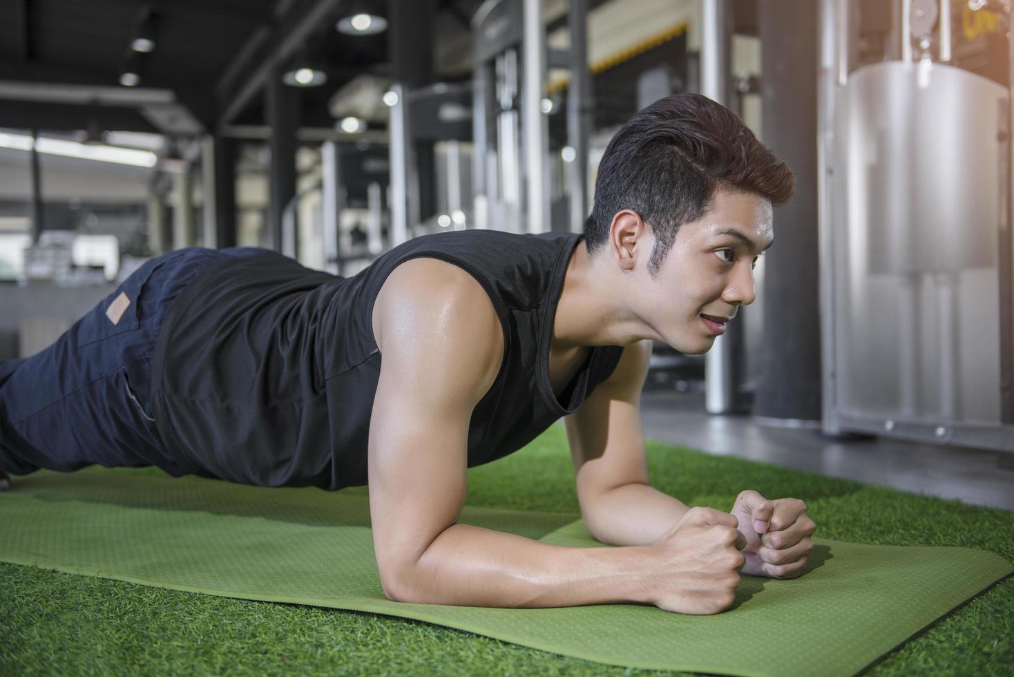 Retrato de un hombre de fitness haciendo ejercicio de tablas en el gimnasio foto