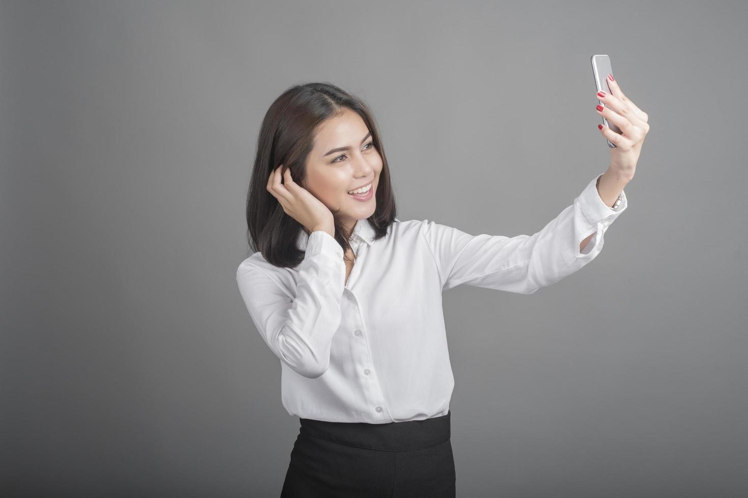 Hermosa mujer de negocios con smartphone sobre fondo gris foto