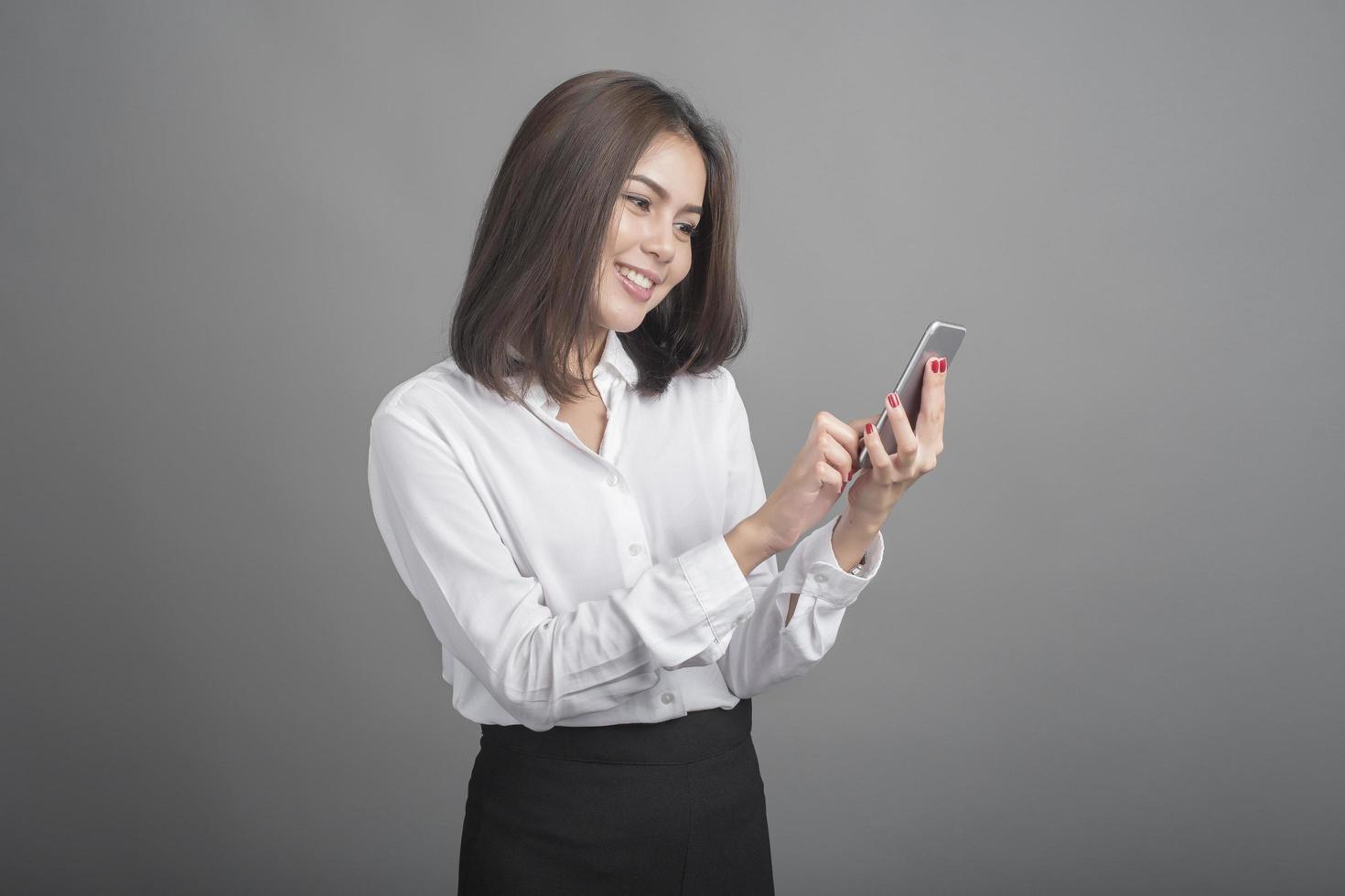 Hermosa mujer de negocios con smartphone sobre fondo gris foto