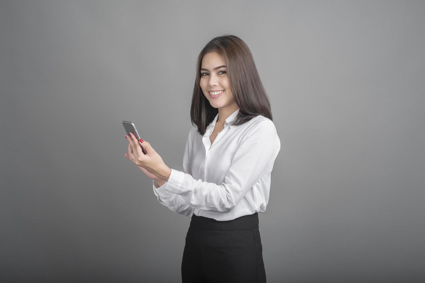 Hermosa mujer de negocios con smartphone sobre fondo gris foto