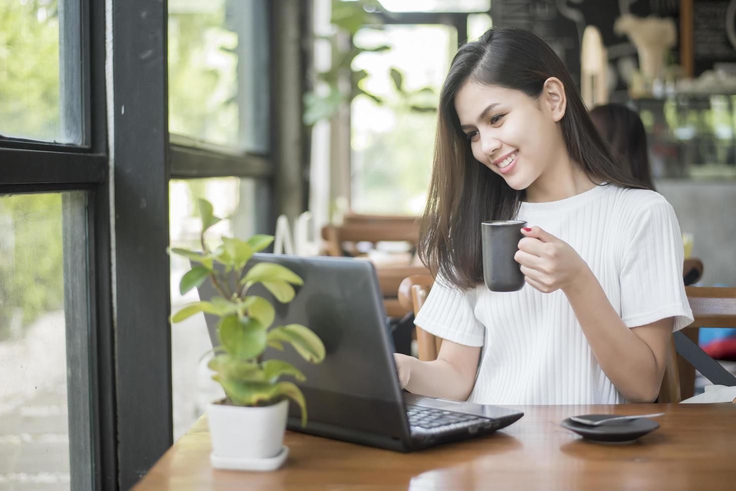 hermosa chica de negocios trabajando con tableta, teléfono inteligente y tomando café en la cafetería foto