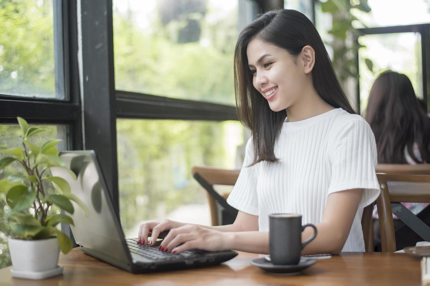 hermosa chica de negocios trabajando con tableta, teléfono inteligente y tomando café en la cafetería foto