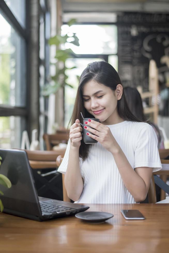 hermosa chica de negocios trabajando con tableta, teléfono inteligente y tomando café en la cafetería foto