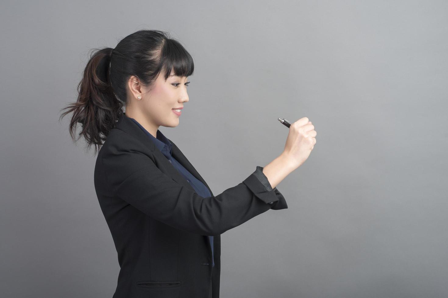 Hermosa mujer de negocios escribiendo algo sobre fondo gris foto