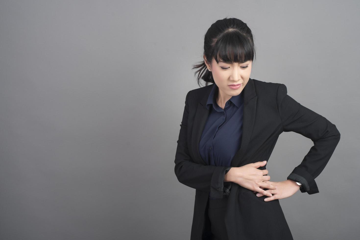 mujer de negocios, dolor de espalda, en, fondo gris foto