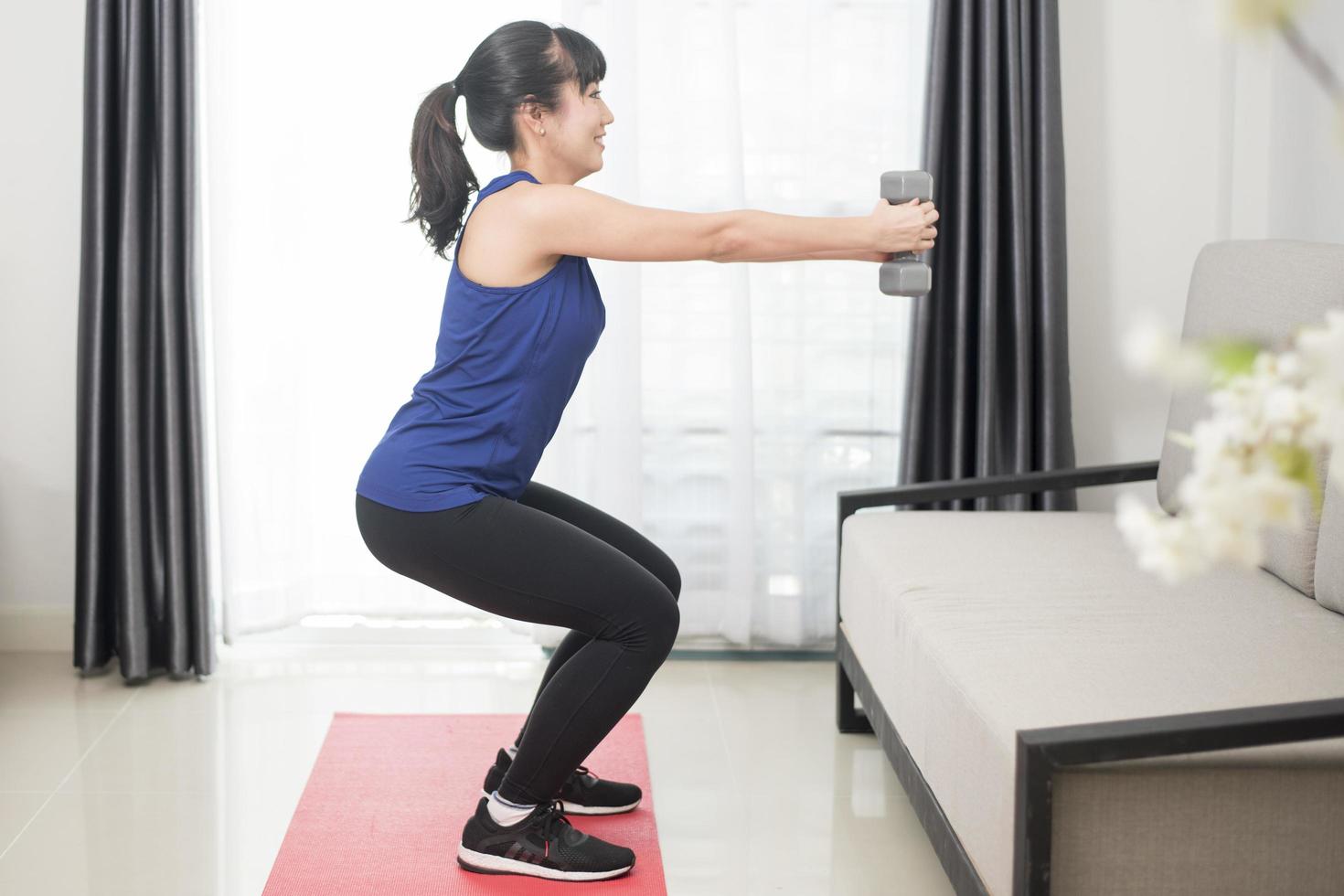 Joven y bella mujer deportiva haciendo sentadillas en casa foto