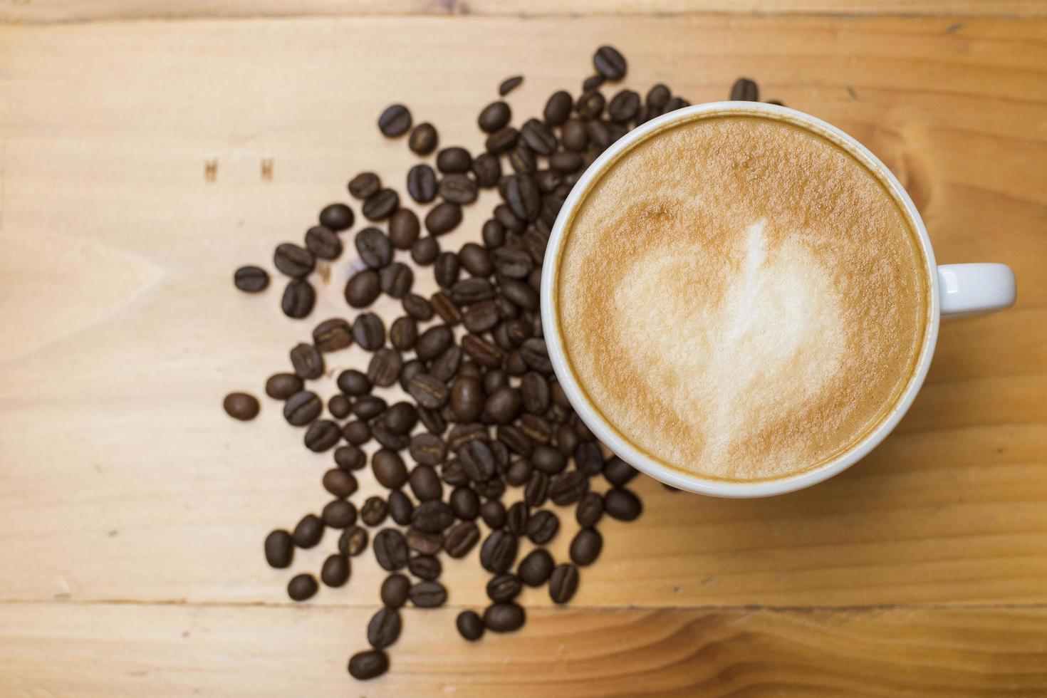 Arte latte con granos de café en la mesa de madera foto