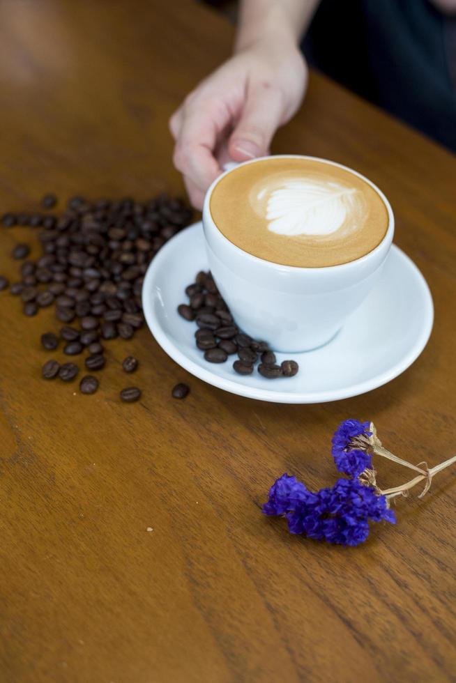 Taza de café y granos de café en la mesa sobre un escritorio de madera foto