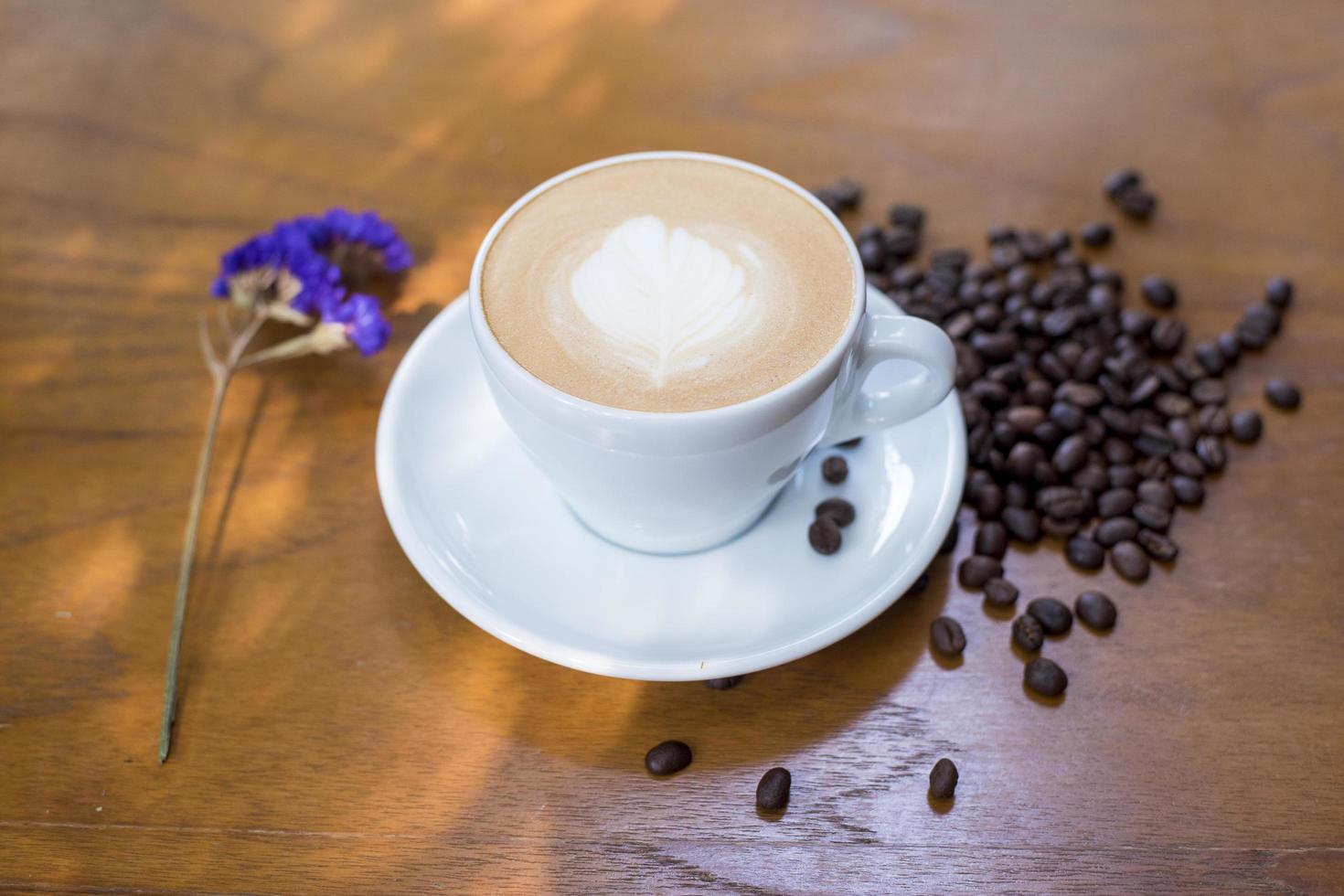 Taza de café y granos de café en la mesa sobre un escritorio de madera foto