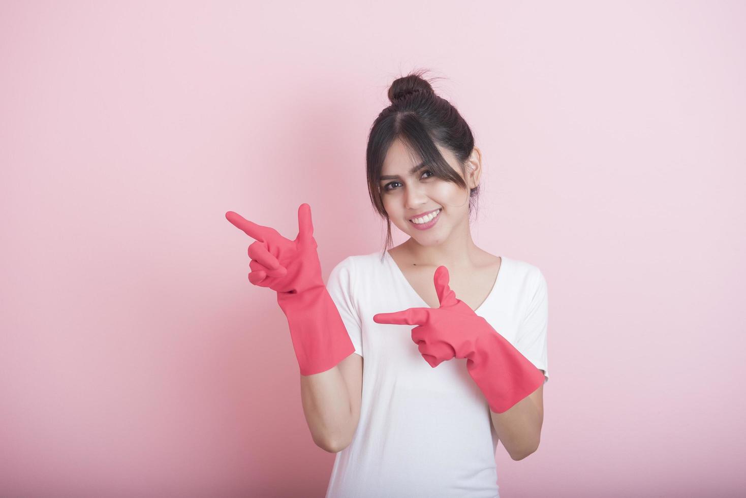 Hermosa ama de casa asiática sonriendo sobre fondo rosa foto