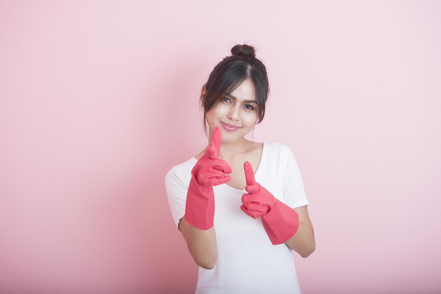 Hermosa ama de casa asiática sonriendo sobre fondo rosa foto