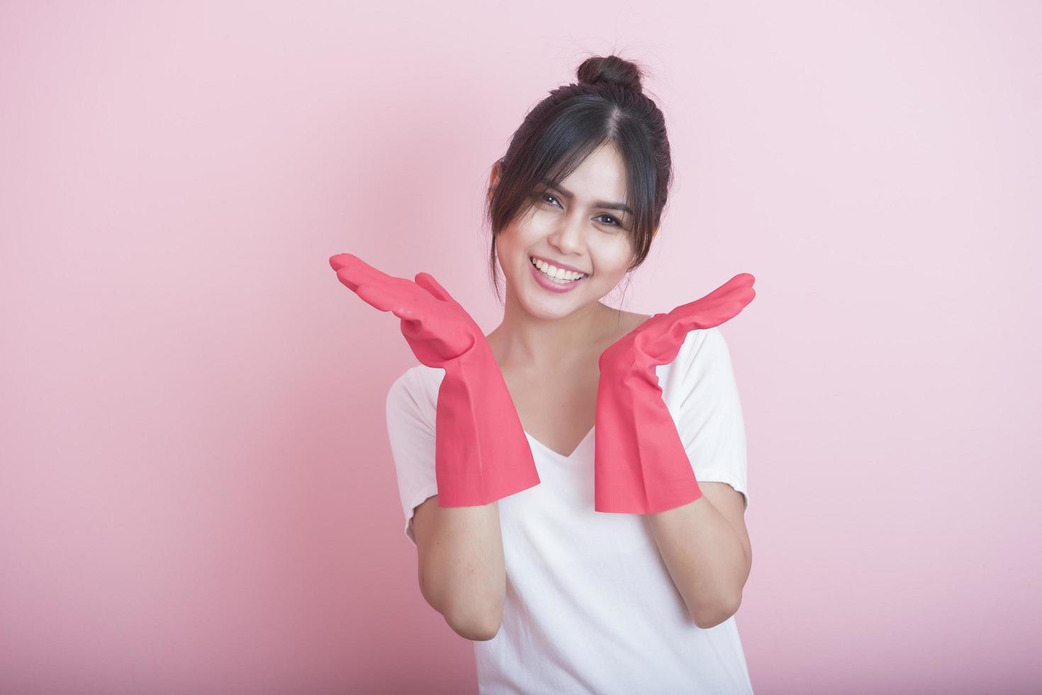 Hermosa ama de casa asiática sonriendo sobre fondo rosa foto