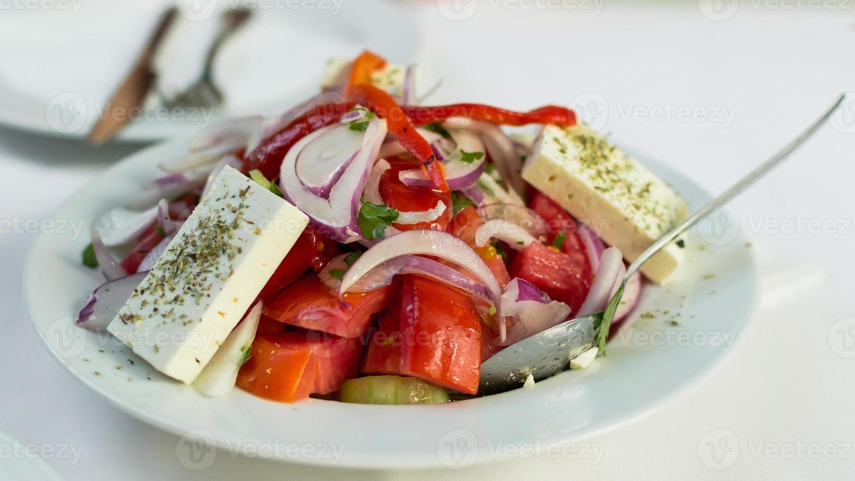 Greek salad with feta on a plate with tasty selection of vegetables photo