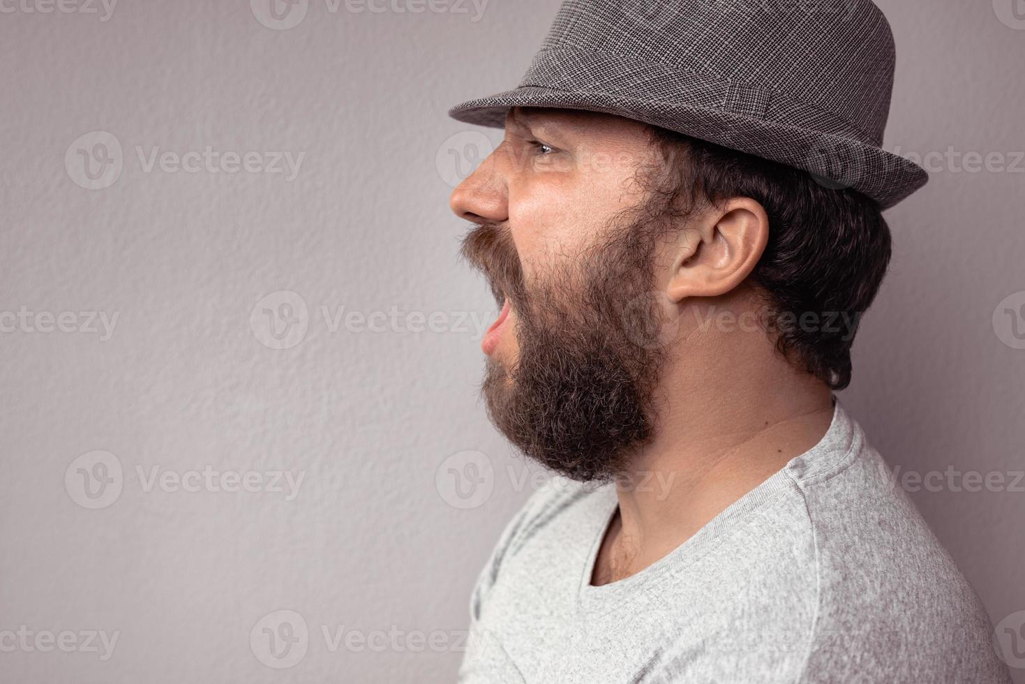 Side portrait of a bearded man shouting photo