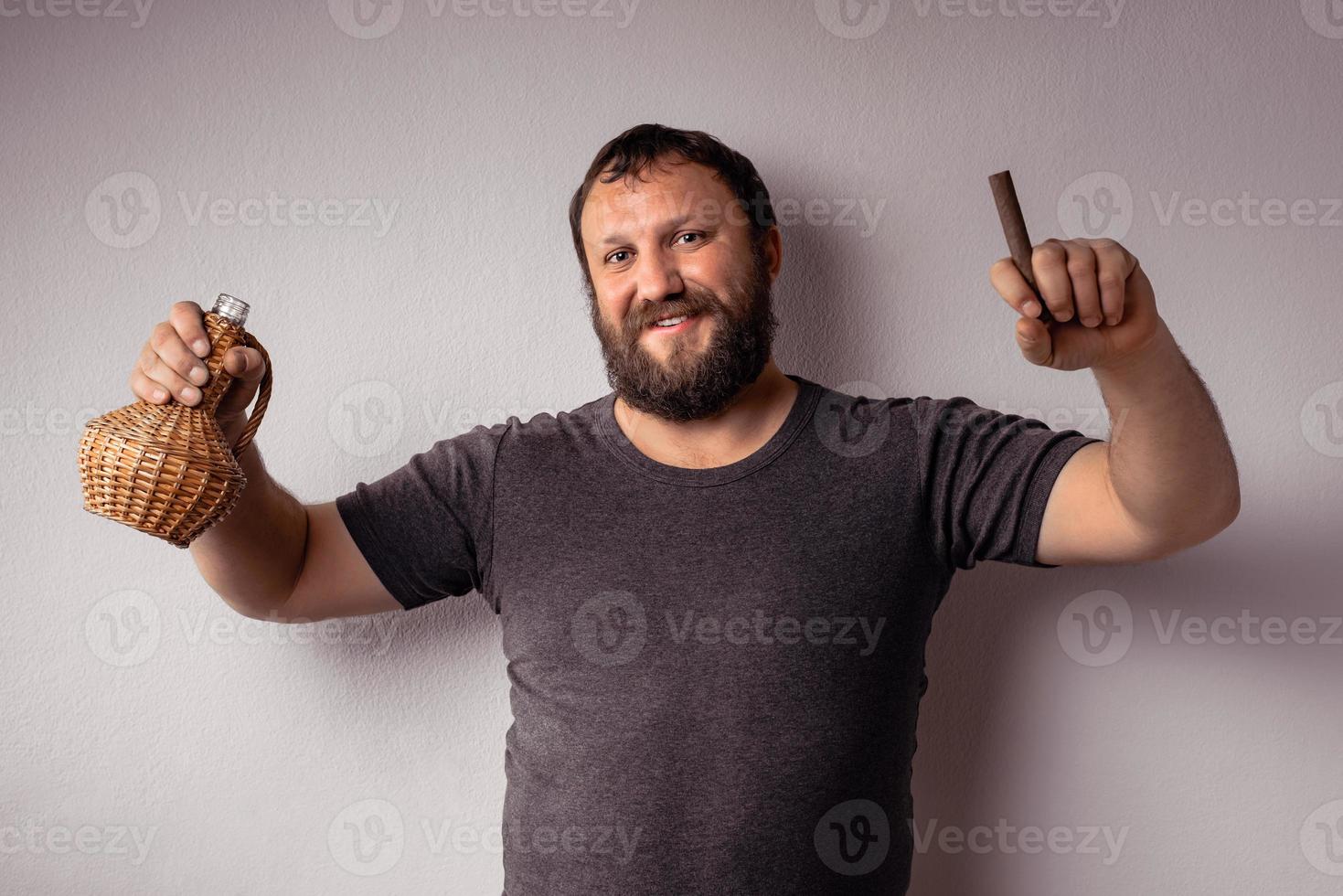 hombre barbudo sostiene una botella de alcohol y cigarro foto