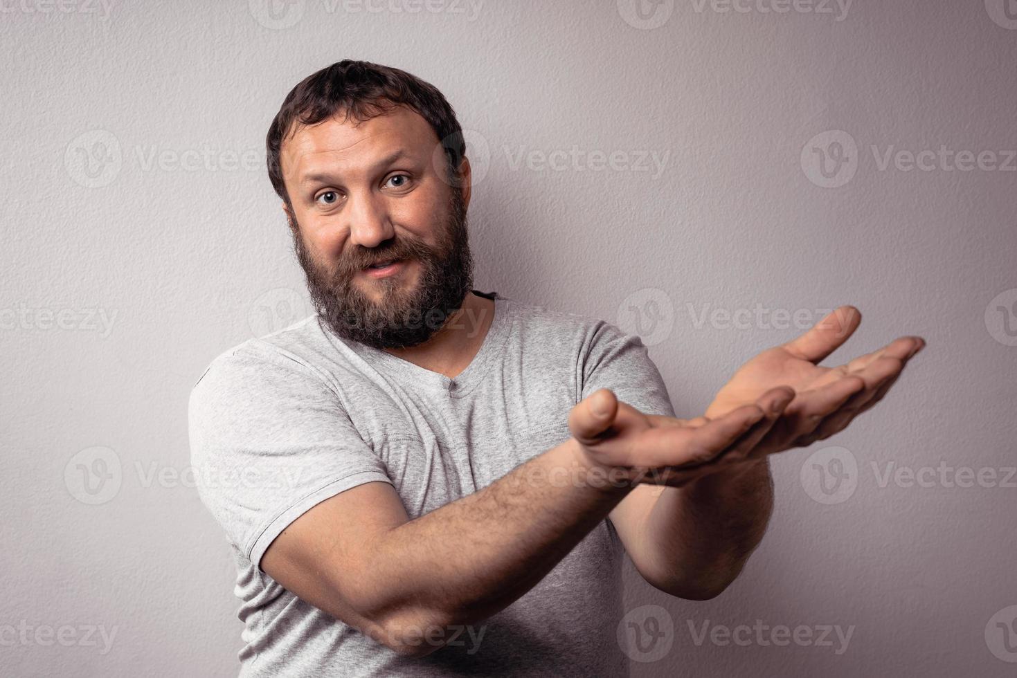 Handsome bearded man in gray t-shirt giving a presentation with his hands photo