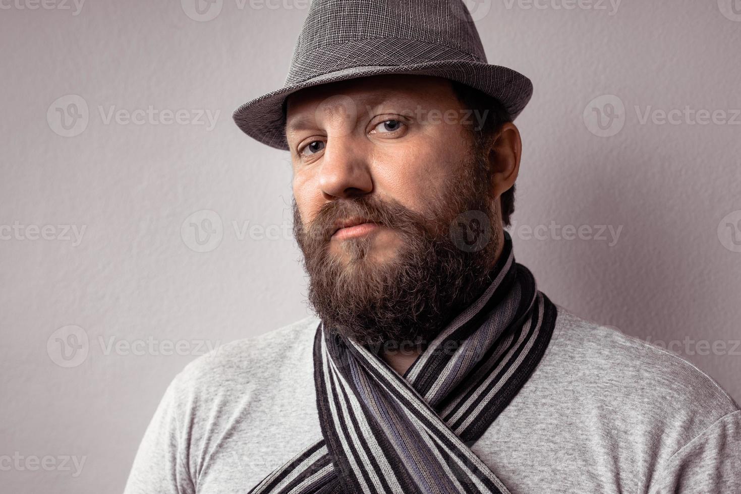 Bearded young hipster man wearing gray hat and scarf photo