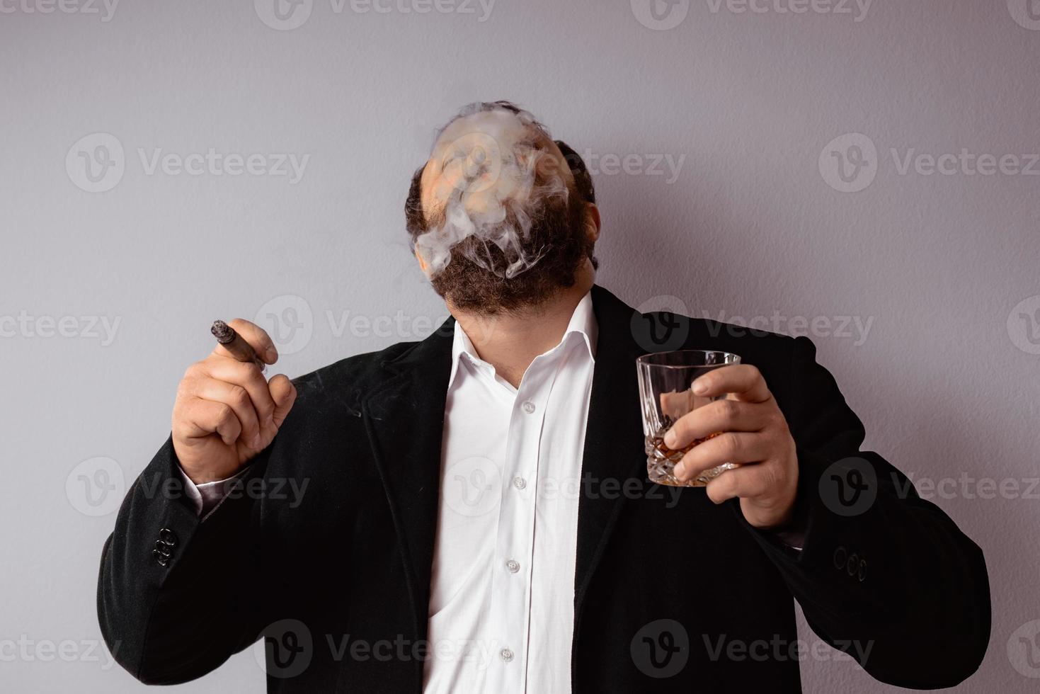 Hombre barbudo en abrigo moderno y camisa fumando su cigarro foto