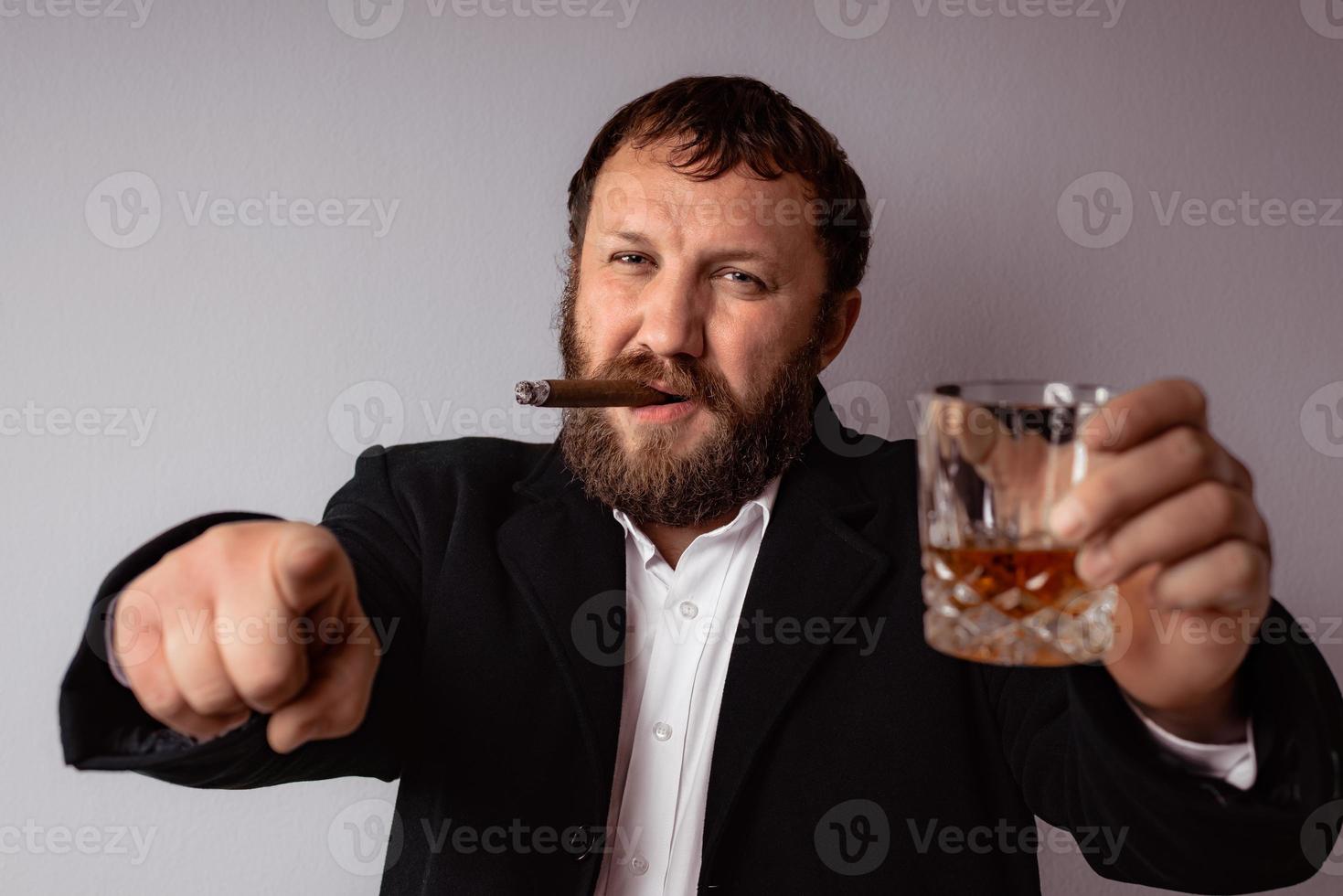 Hombre barbudo en abrigo moderno y camisa fumando su cigarro foto