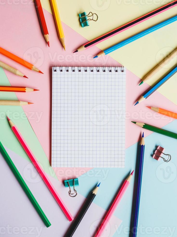 cuaderno escolar y lápices, sobre un fondo multicolor. concepto de educación. De vuelta a la escuela. foto