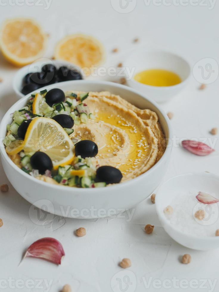 Hummus from chickpeas, with olive oil, olives, lemon, garlic, sesame seeds, onions and cucumbers. photo