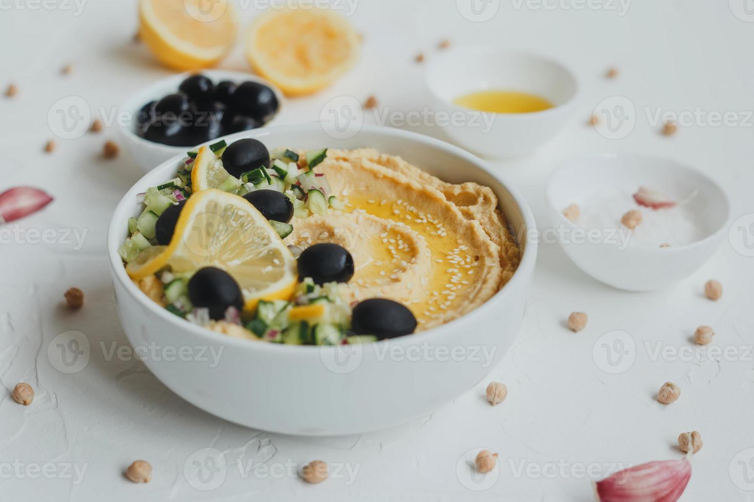 Hummus from chickpeas, with olive oil, olives, lemon, garlic, sesame seeds, onions and cucumbers. photo