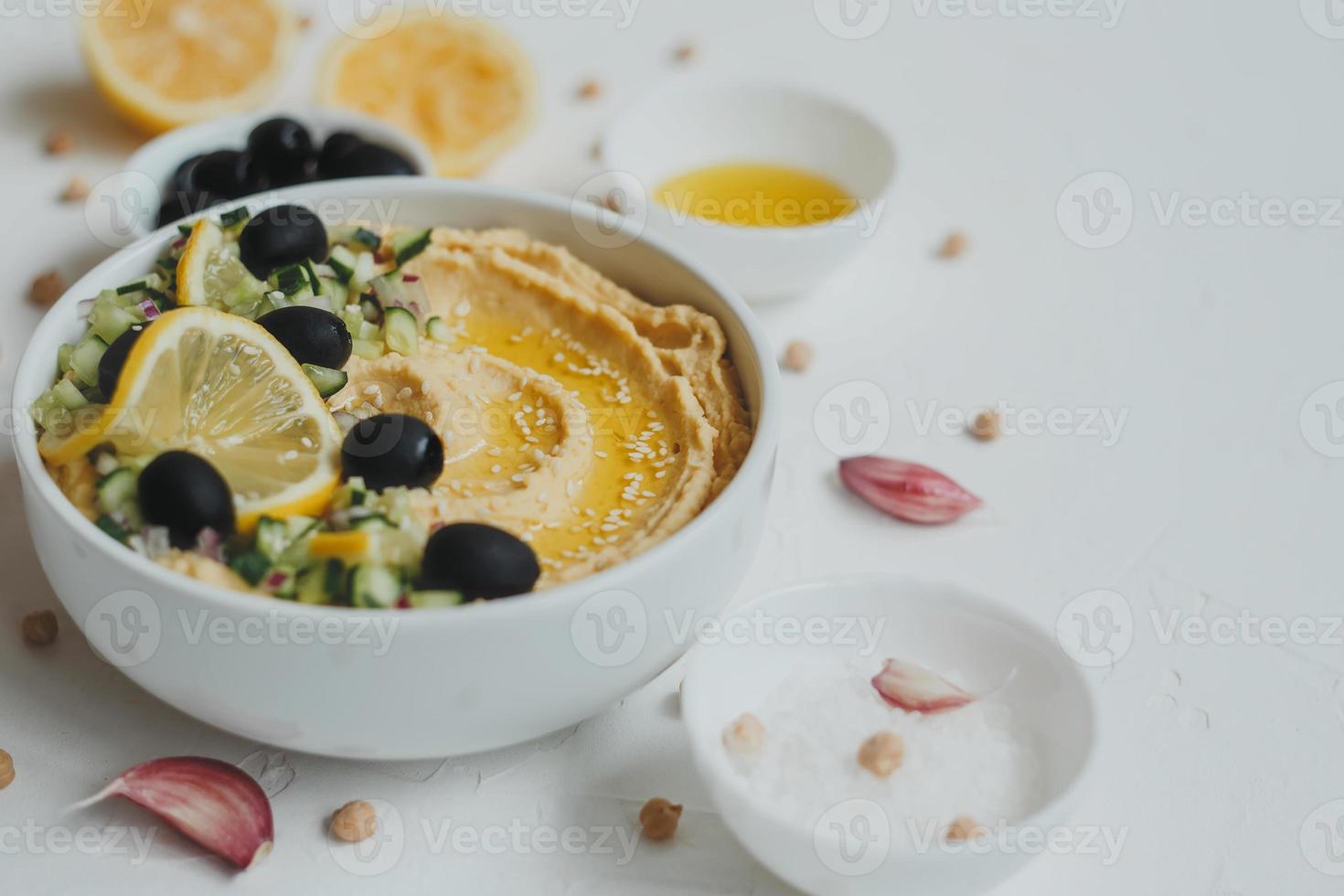 Hummus from chickpeas, with olive oil, olives, lemon, garlic, sesame seeds, onions and cucumbers. photo