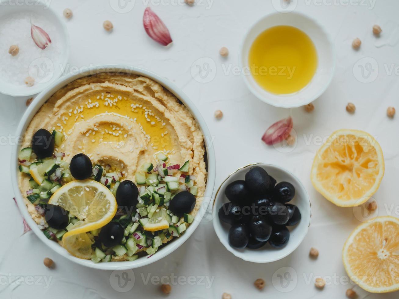 Hummus from chickpeas, with olive oil, olives, lemon, garlic, sesame seeds, onions and cucumbers. photo