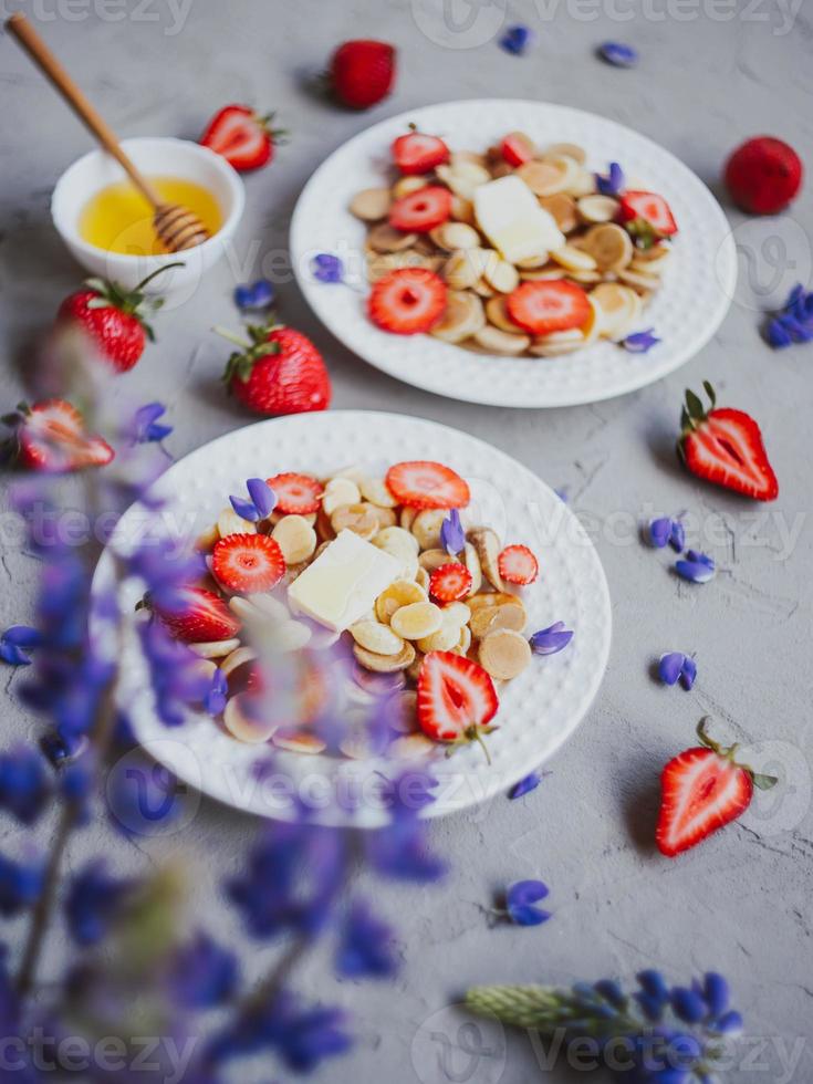 cereal para panqueques, comida de moda. mini tortitas de cereales con mantequilla, miel y fresas. foto