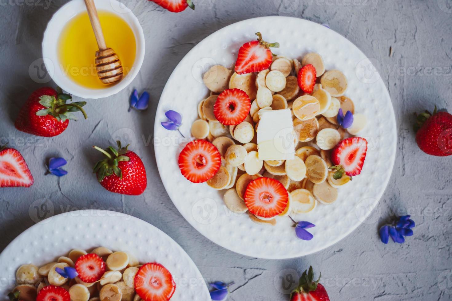 cereal para panqueques, comida de moda. mini tortitas de cereales con mantequilla, miel y fresas. foto