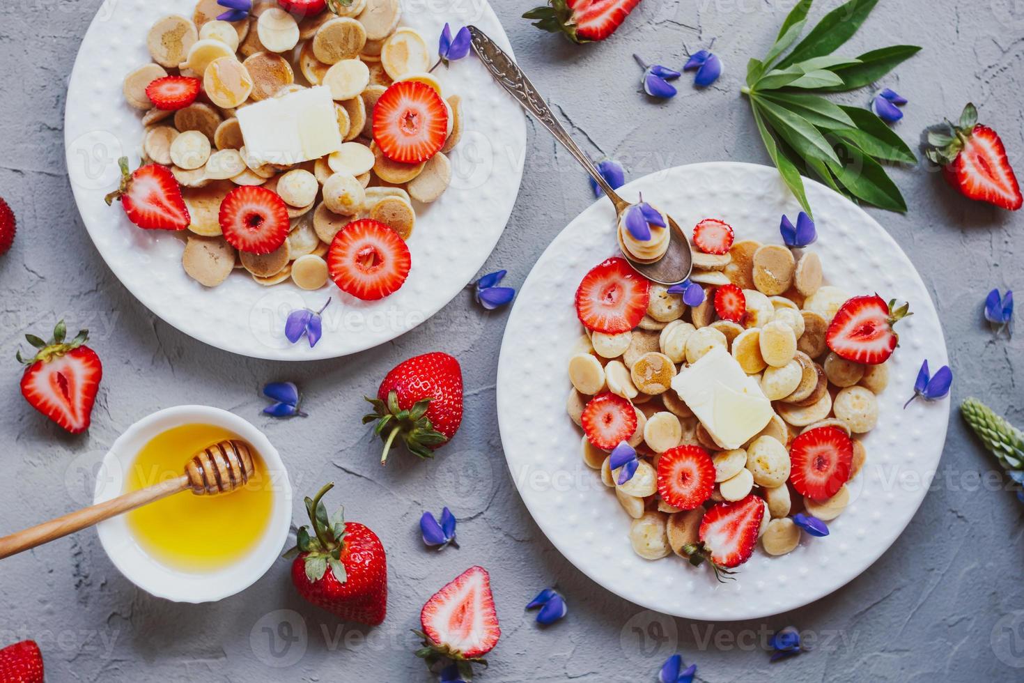 Pancake cereal, trendy food. Mini cereal pancakes with butter, honey, and strawberries. photo
