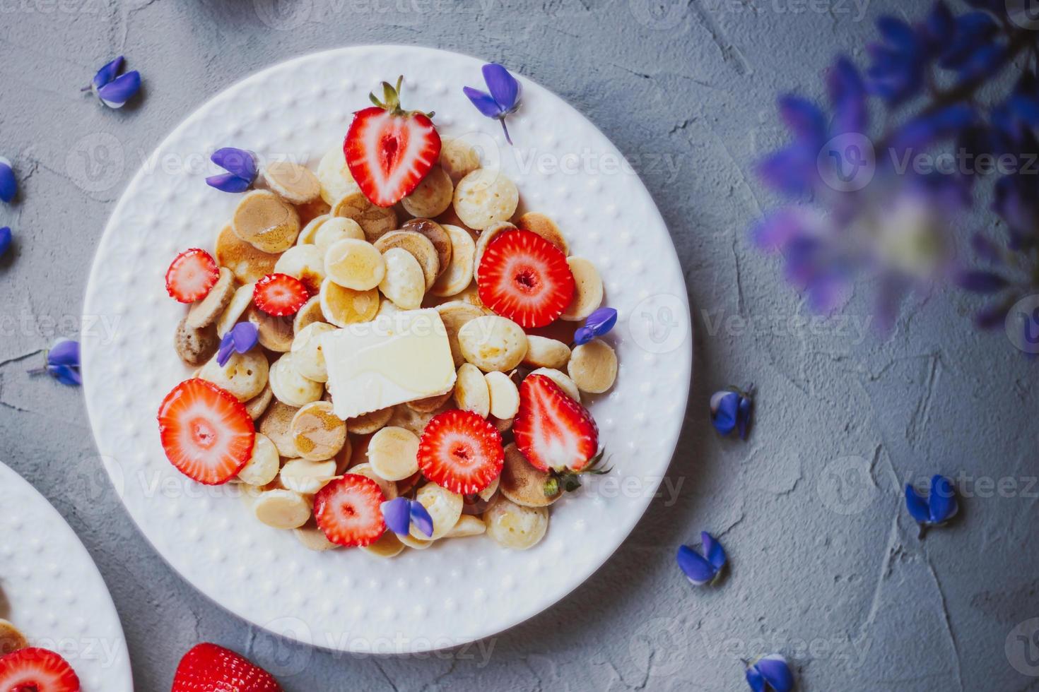 cereal para panqueques, comida de moda. mini tortitas de cereales con mantequilla, miel y fresas. foto